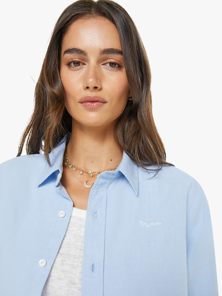 Close up view of  woman in a light blue classic button-up with a curved hem and MOTHER's name embroidered on the chest.