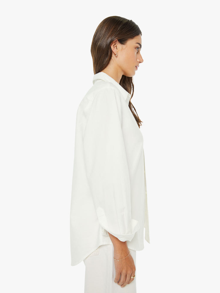 Side view of a woman in a white classic button-up with a curved hem and MOTHER's name embroidered on the chest.