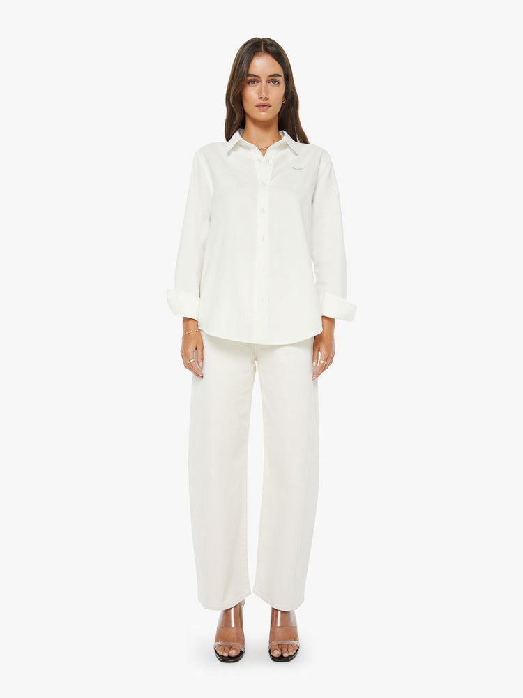 Full body view of a woman in a white classic button-up with a curved hem and MOTHER's name embroidered on the chest.