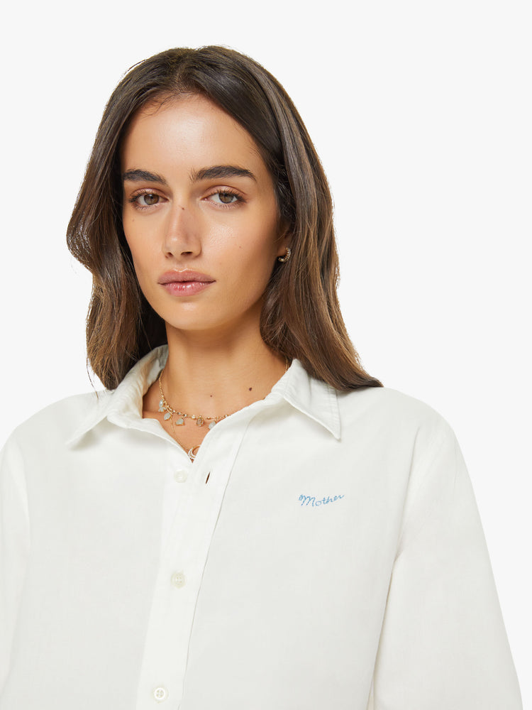 Close up view of a woman in a white classic button-up with a curved hem and MOTHER's name embroidered on the chest.