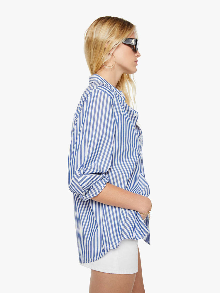 Side view of a woman in a blue and white stripes button-up shirt with a curved hem and MOTHER's name embroidered with two small palm trees on the chest.