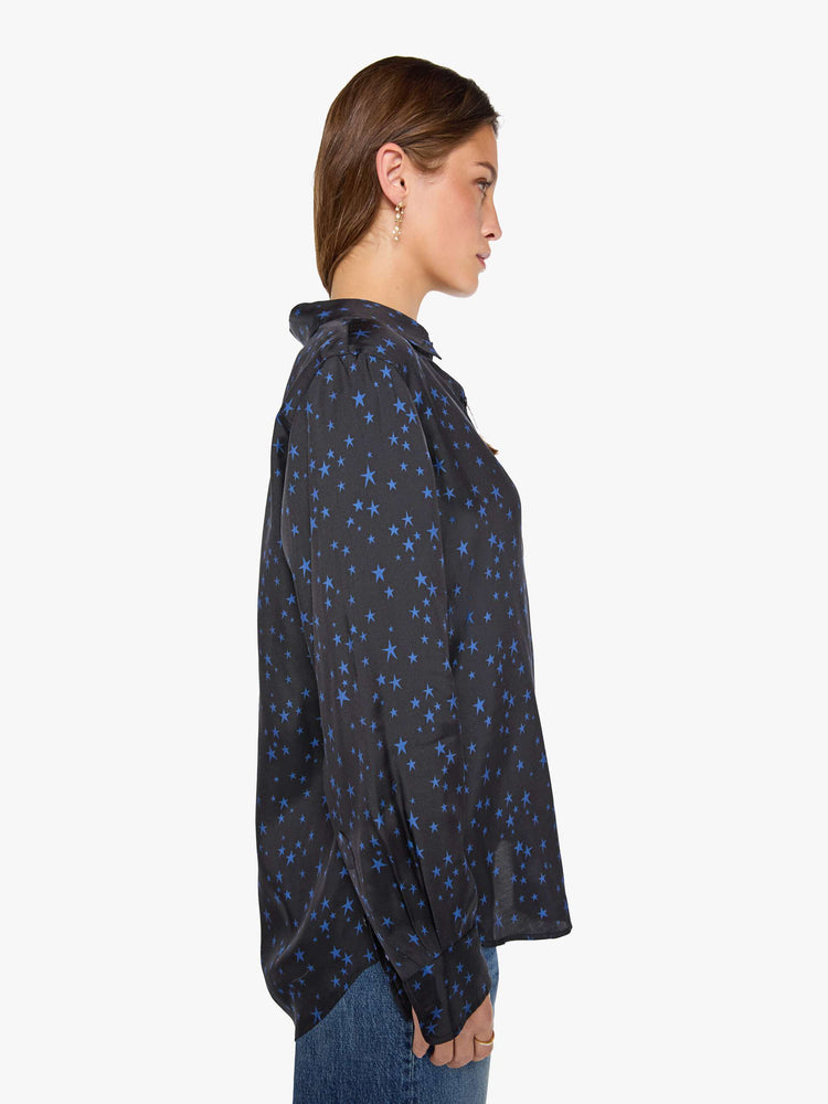 Side view of a woman in a black with navy stars throughout classic button up. 