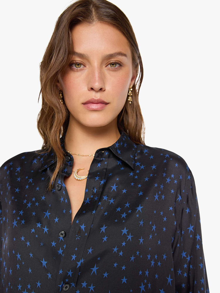 Close up view of a woman in a black with navy stars throughout classic button up. 