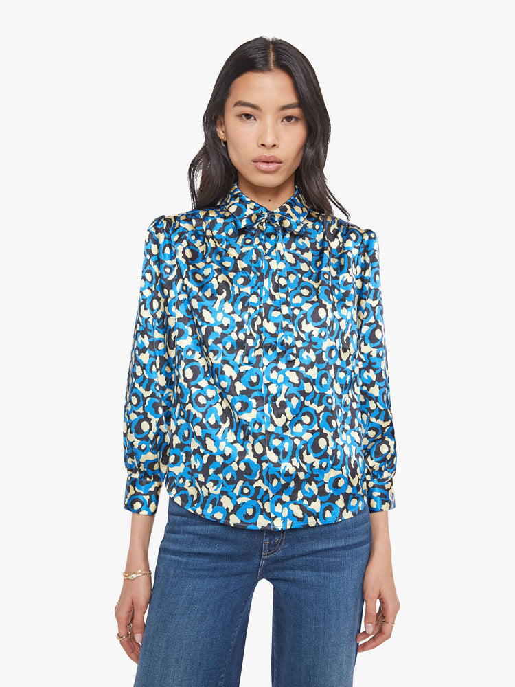 Front view of a woman in a collared button-up blouse with puff shoulders, cropped sleeves and a slightly curved hem.