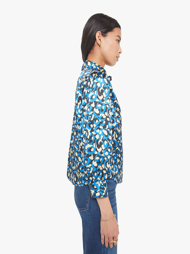 Side view of a woman in a collared button-up blouse with puff shoulders, cropped sleeves and a slightly curved hem.