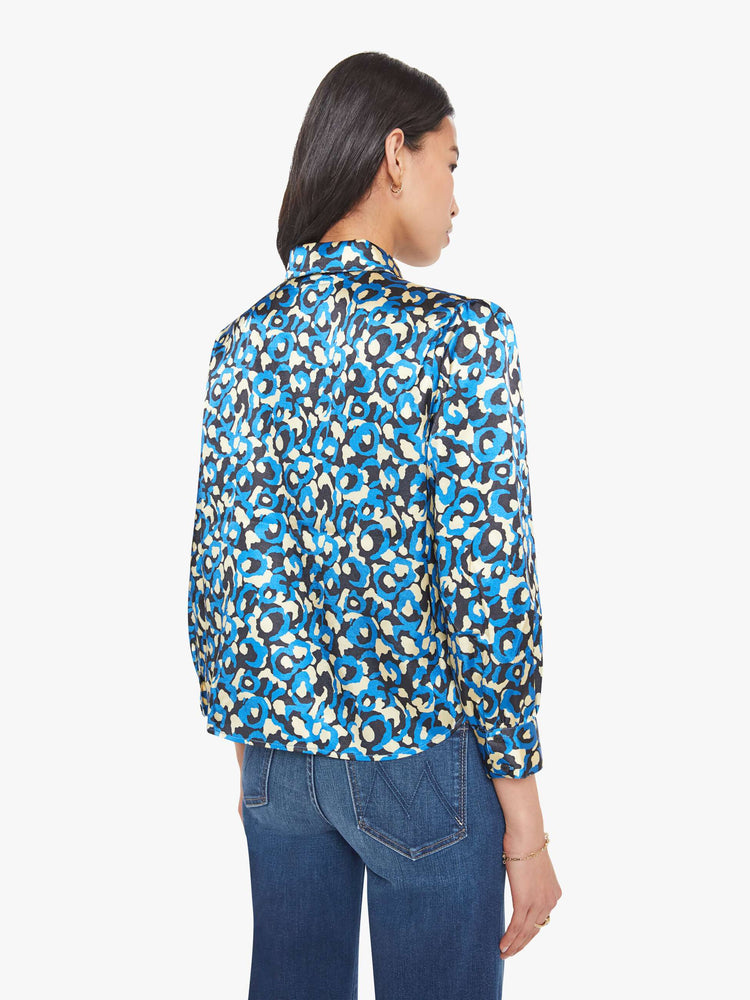 Back view of a woman in a collared button-up blouse with puff shoulders, cropped sleeves and a slightly curved hem.