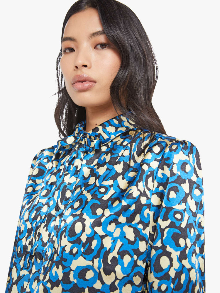 Close up view of a woman in a collared button-up blouse with puff shoulders, cropped sleeves and a slightly curved hem.