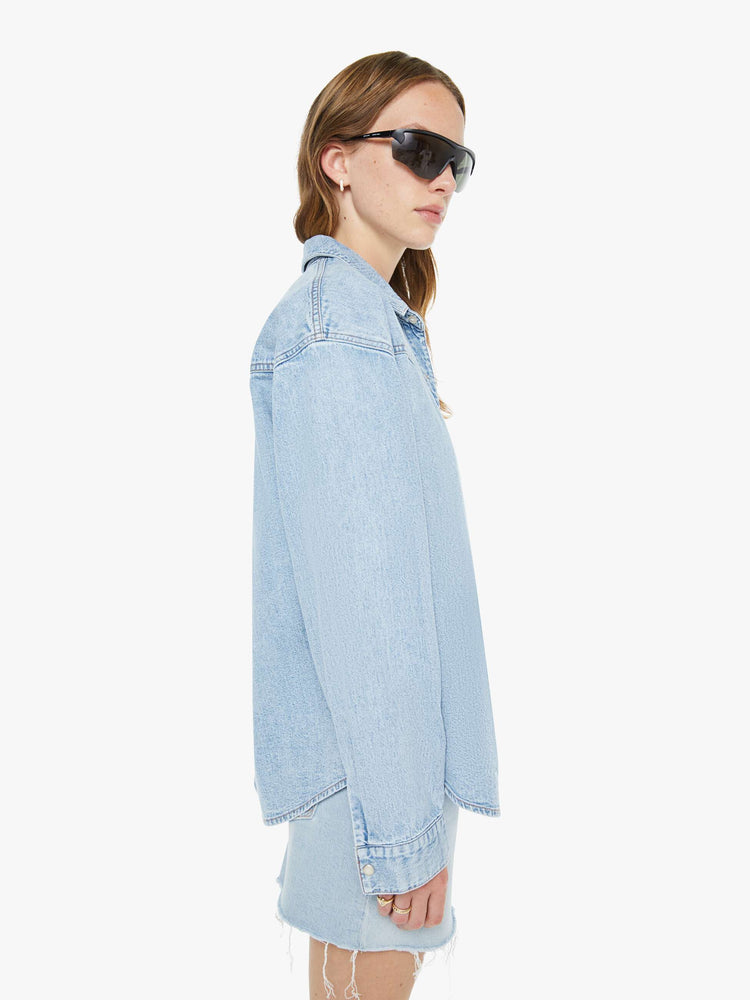 Side view of a woman in a denim button-up with drop shoulders, a front patch pocket and faux-pearl snaps down the front.