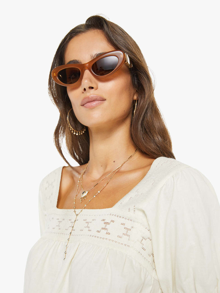 Close up view of a woman in an off white square-neck blouse with short puff sleeves and a loose, flowy fit.