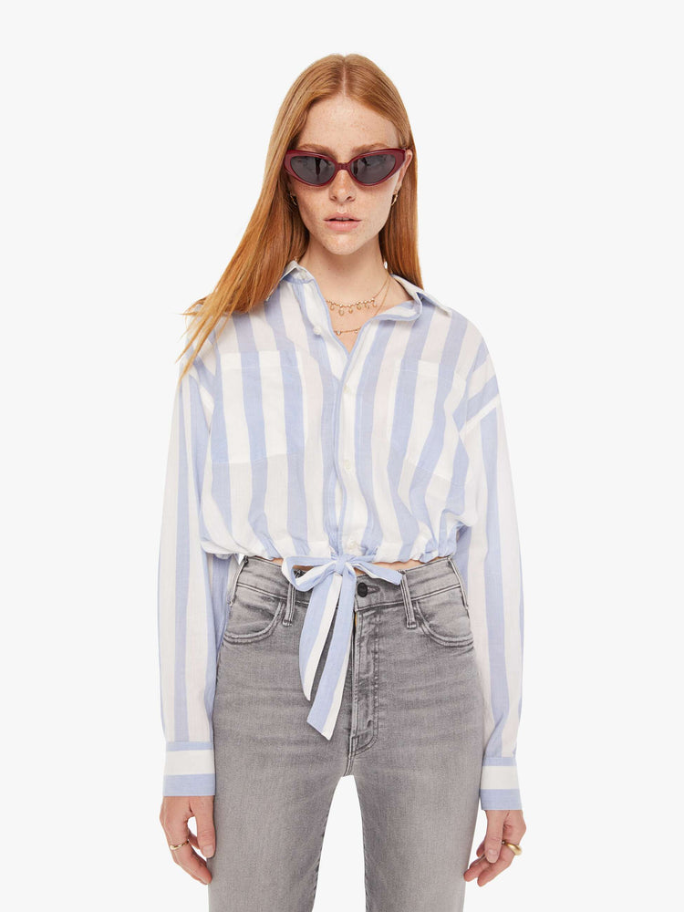 Front view of a womens button down shirt featuring a white a light blue stripe pattern and a cropped waist tie.