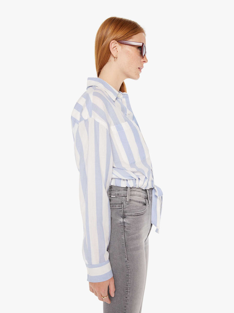 Side view of a womens button down shirt featuring a white a light blue stripe pattern and a cropped waist tie.