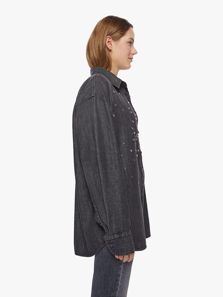 Side view of a woman faded black with jewels on chest oversized button-up with long sleeves and a curved hem.