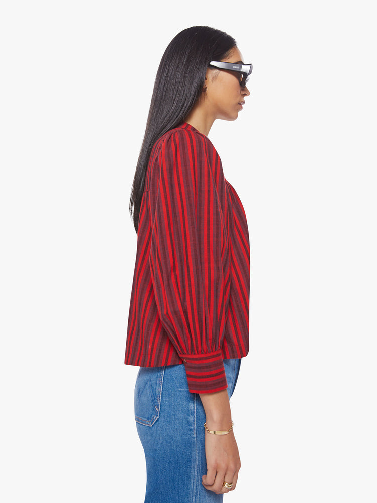 Side view of a women red, grey, black stripe pattern blouse with a buttoned V-neck, puffed 3/4-sleeves and a slightly cropped hem.