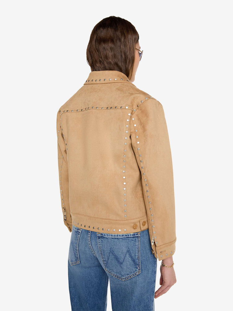Back view of a woman in a khaki faux suede jacket features studded details throughout and off-white lining with navy doodles.