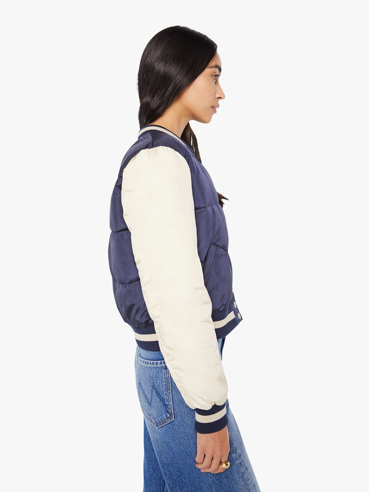 Side  view of navy quilted letterman jacket with a crewneck, snaps down the front, ribbed hems and a slightly cropped fit.