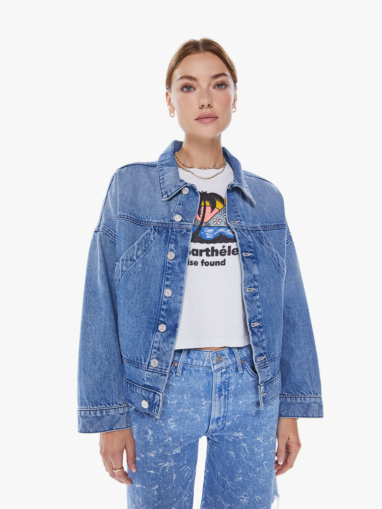Front view of woman's denim jacket with drop shoulders, slit pockets at the chest, seamed details and a boxy fit in mid blue wash.