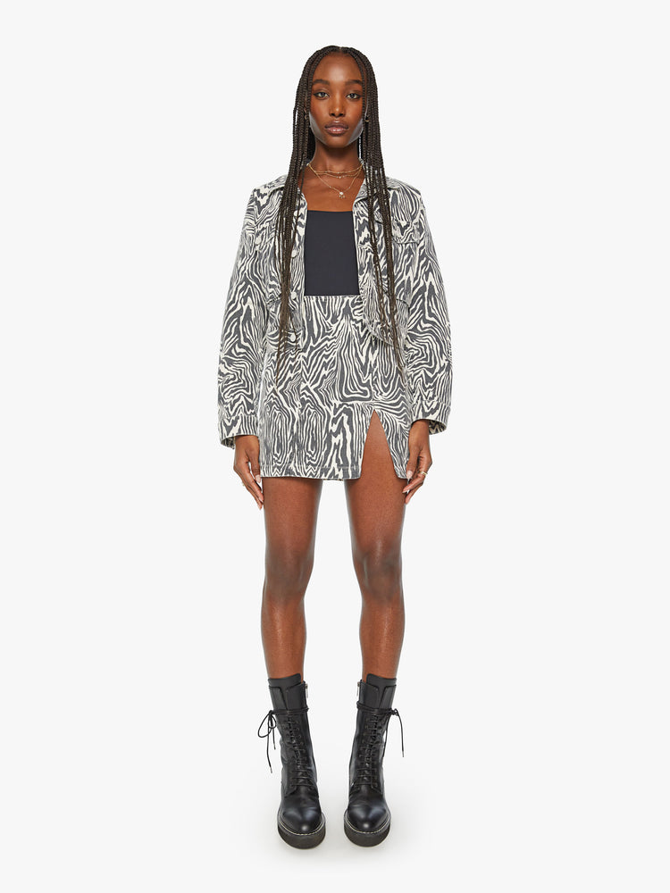Full body view of a woman denim boxy fit with oversized patch pockets and slight cropped hem jacket in a black and white zebra print.