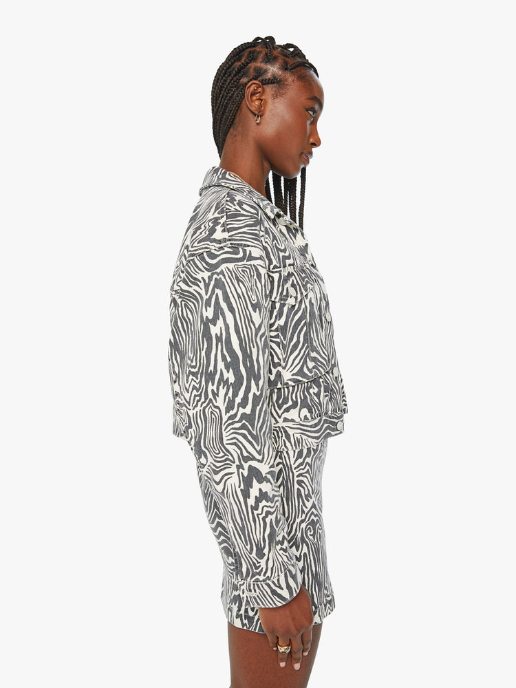 Side view of a woman denim boxy fit with oversized patch pockets and slight cropped hem jacket in a black and white zebra print.
