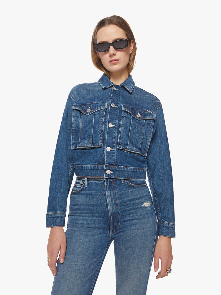 Front view of a dark blue wash denim jacket has a shrunken, boxy fit with oversized patch pockets and a slightly cropped hem.