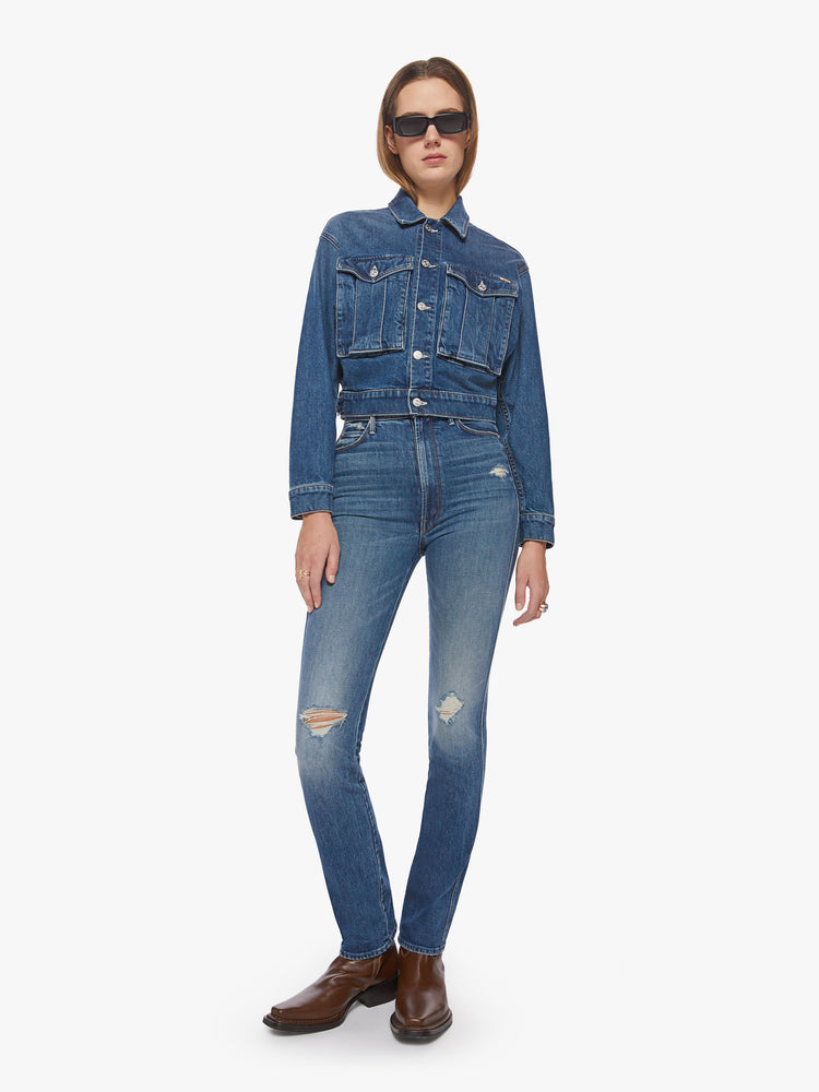 Full body view of a dark blue wash denim jacket has a shrunken, boxy fit with oversized patch pockets and a slightly cropped hem.