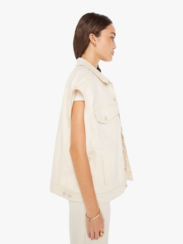 Side view of a woman creamy white hue oversized vest with extra-wide shoulders, patch pockets and a super boxy fit.