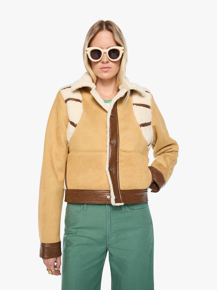 Front view of a woman in a faux-shearling panels at the shoulders, a faux-shearling collar and brown faux-leather trim collared button-up jacket with a cropped hem and a boxy fit. 