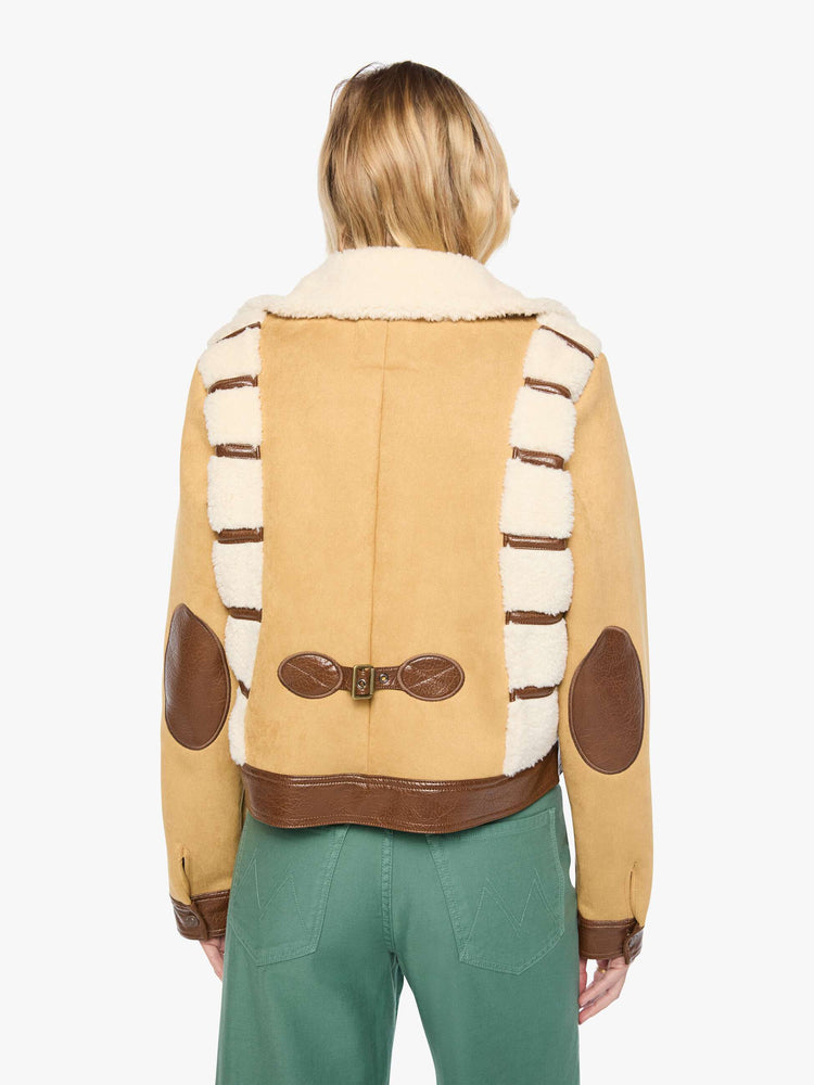Back view of a woman in a faux-shearling panels at the shoulders, a faux-shearling collar and brown faux-leather trim collared button-up jacket with a cropped hem and a boxy fit. 