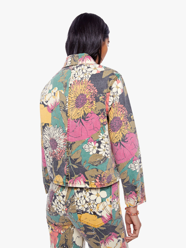 Back view of a woman faded floral print denim jacket with oversized front patch pockets, cropped long sleeves and a boxy, shrunken fit.