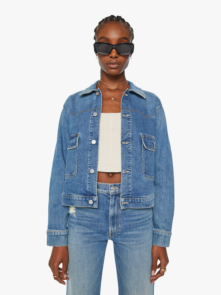 Front view of a woman boxy denim jacket with Western-inspired stitching across the chest, drop shoulders and oversized patch pockets in a med blue wash.