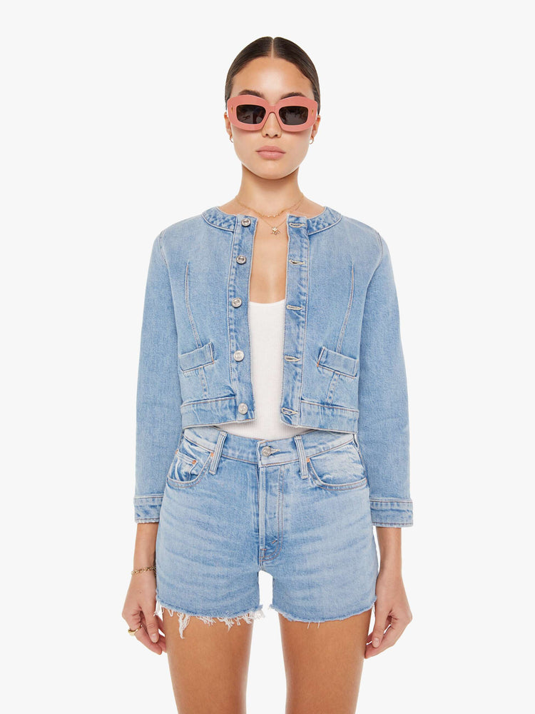 Front view of a light blue wash denim jacket featuring a curved crew neck and a cropped fit.