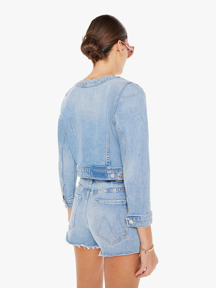 Back view of a light blue wash denim jacket featuring a curved crew neck and a cropped fit.