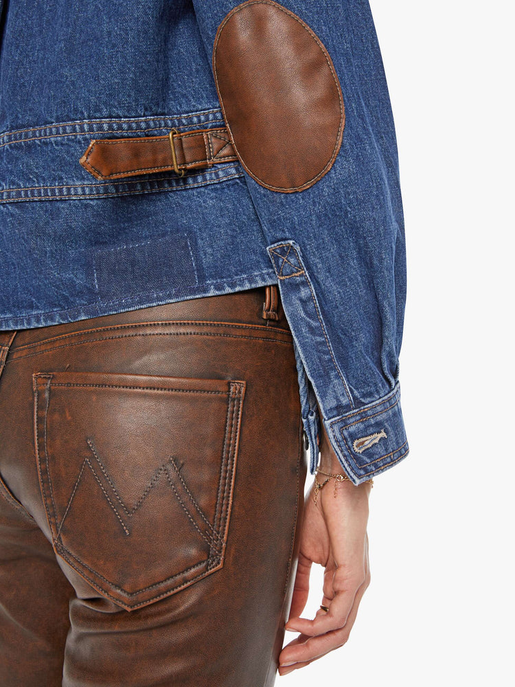 Swatch view of a woman in a denim jacket with brown faux-leather patches on the shoulders and adjustable tabs on the waist.