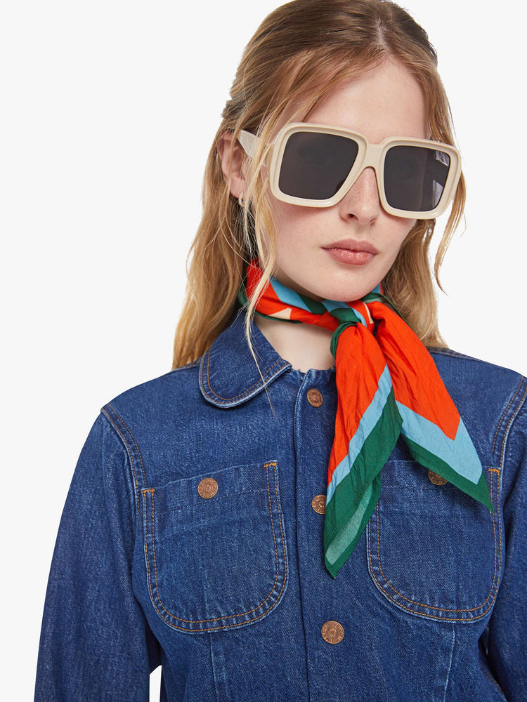 Close up view of a woman in a mid blue shrunken denim jacket with patch pockets and a cropped hem. 