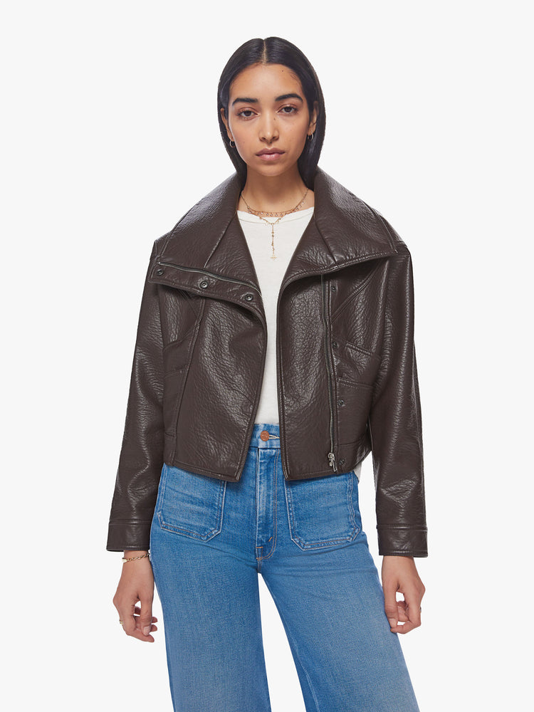 Front view of a woman brown faux leather jacket with a dramatically oversized collar, front slit pockets, drop shoulders and a hidden zip closure with buttons down the front.
