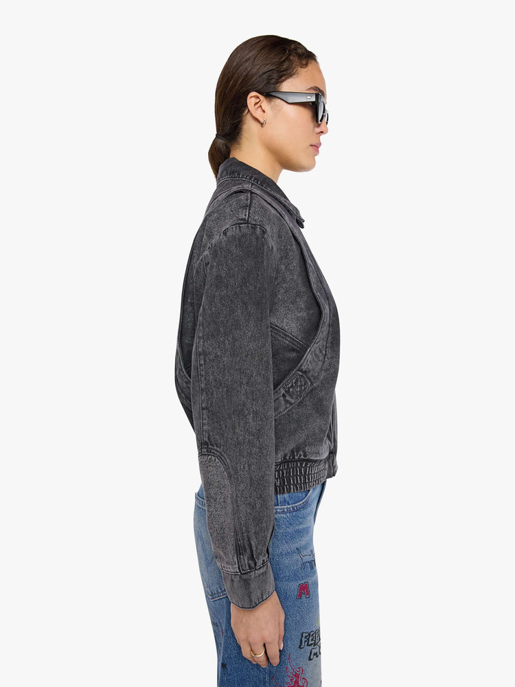 Side view of a woman in a faded grey  jacket is designed with drop shoulders, seamed details, hidden Velcro pockets, an elastic hem and a zip closure with a button flap. 