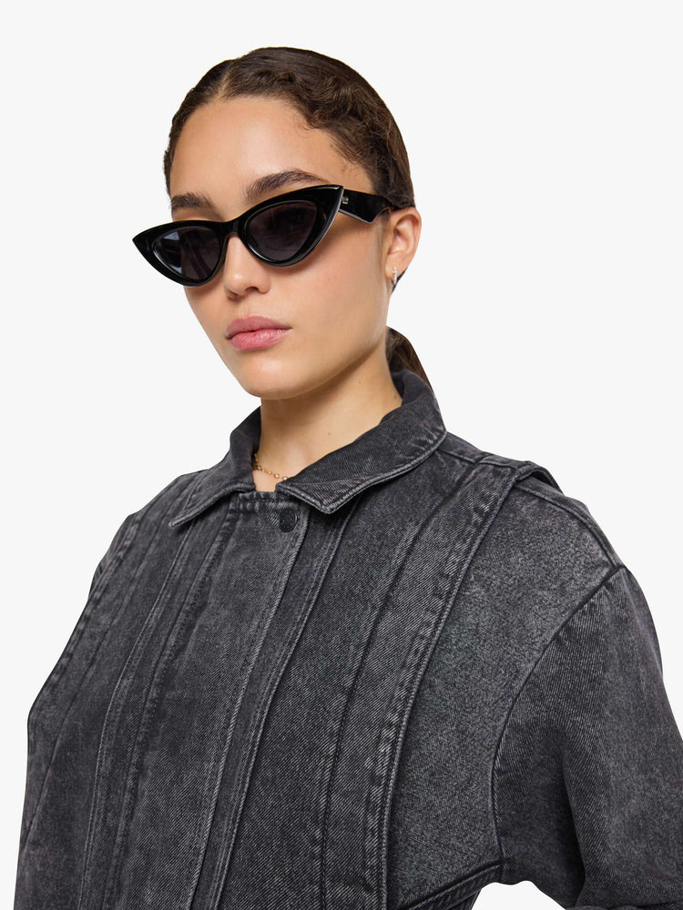 Close up view of a woman in a faded grey  jacket is designed with drop shoulders, seamed details, hidden Velcro pockets, an elastic hem and a zip closure with a button flap. 