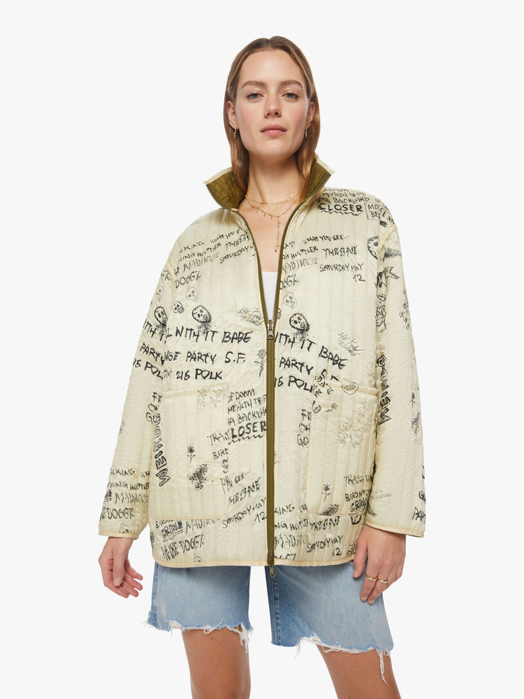 Front view of a woman reversible zip-up jacket with drop shoulders, patch pockets and a boxy fit, cream on the one side with angsty doodles in black and army green on the other side.