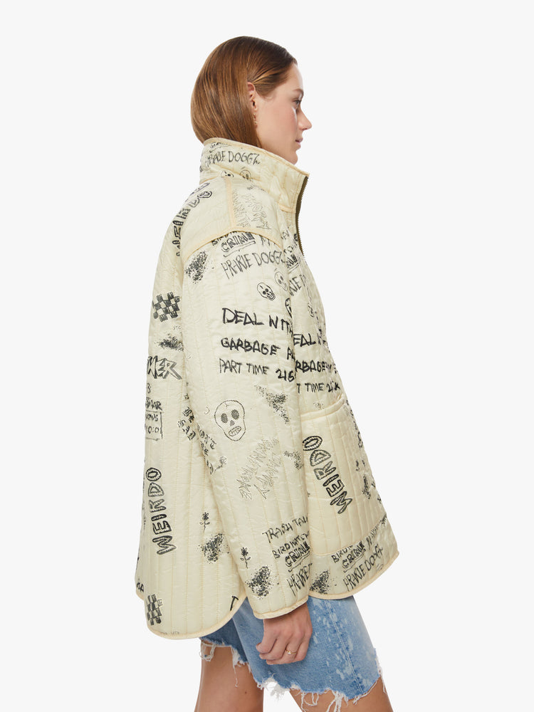 Side view of a woman reversible zip-up jacket with drop shoulders, patch pockets and a boxy fit, cream on the one side with angsty doodles in black and army green on the other side.