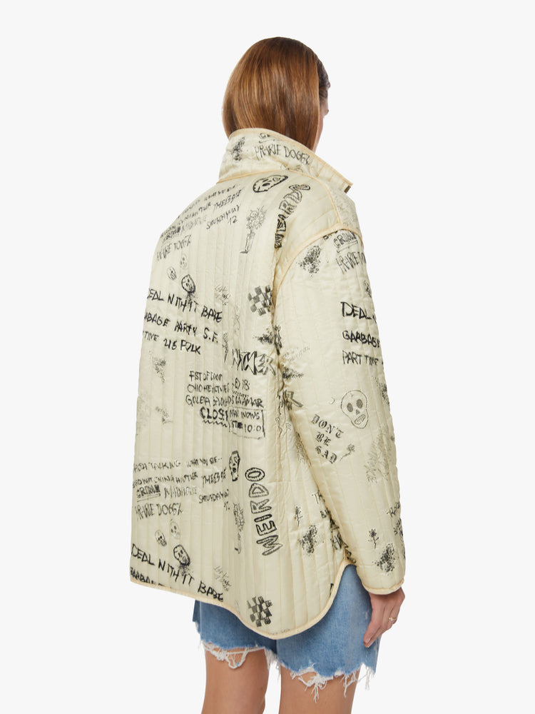 Back view of a woman reversible zip-up jacket with drop shoulders, patch pockets and a boxy fit, cream on the one side with angsty doodles in black and army green on the other side.