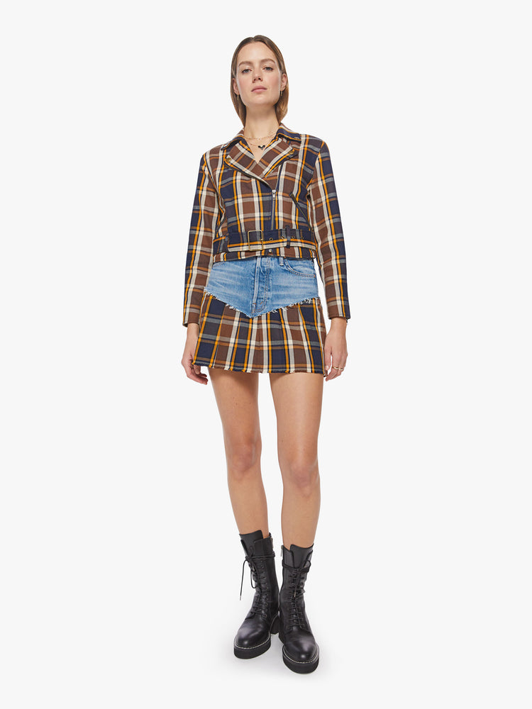 Full body view of a woman cropped moto jacket with a notched collar, zip pockets and a belted waistband in a navy, orange and brown plaid with brass-toned hardware.