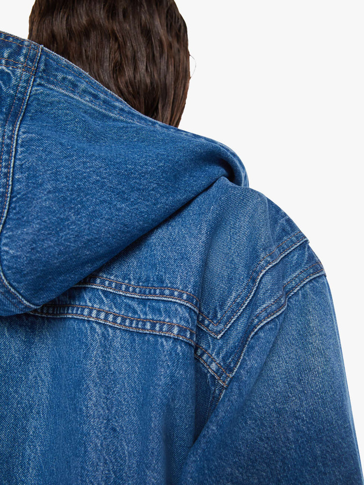 Swatch view of a woman oversized denim jacket with a drawstring hood, extra-wide panels at the shoulders, patch and zip pockets and an extra-long hem in a mid blue wash.