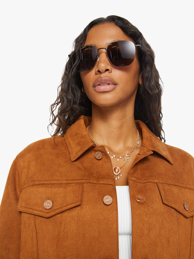 Close up view of a woman classic collared jacket with drop shoulders, front patch pockets and a boxy fit in a light brown faux suede and multi colored studded gems on the back.