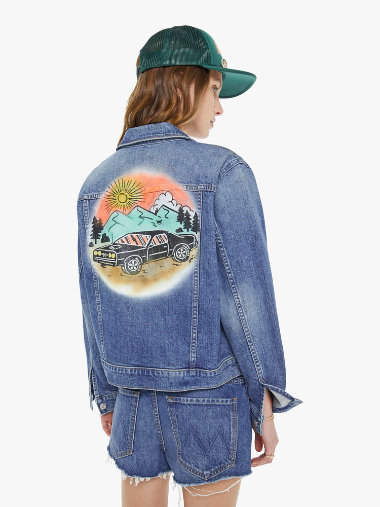 Back view of a woman in mid blue jacket with subtle fading and an airbrushed and screen printed graphic on the back.