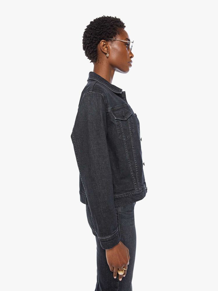 Side view of a woman in  a washed classic denim jacket with front patch pockets and a slightly cropped fit. 
