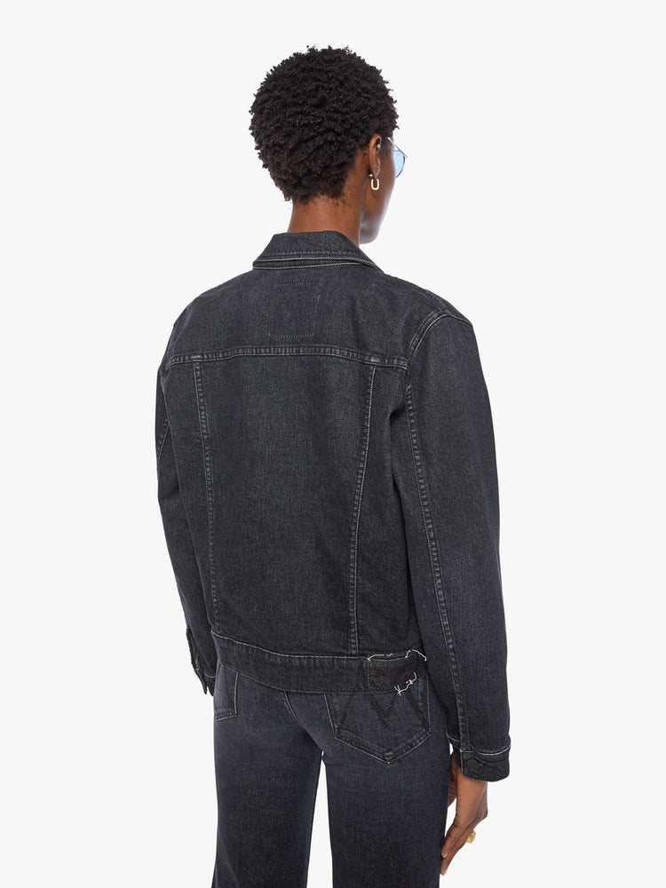 Back view of a woman in  a washed classic denim jacket with front patch pockets and a slightly cropped fit. 