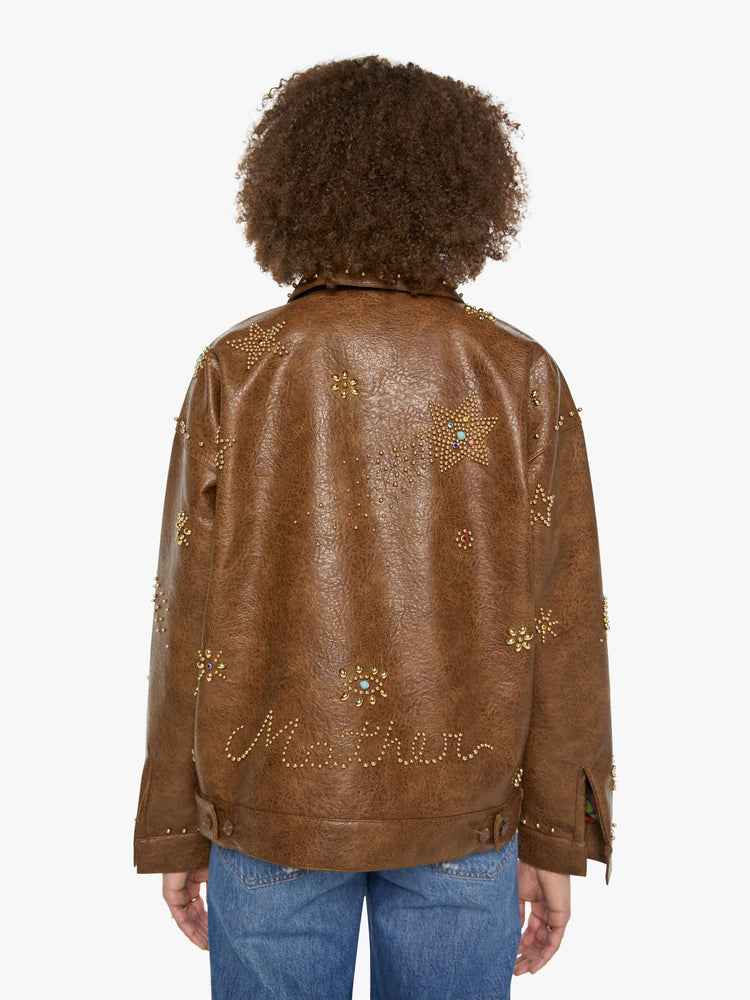 Back view of a woman in a brown faux leather with celestial rhinestone details boxy jacket with drop shoulders, a zip closure and an oversized fit.