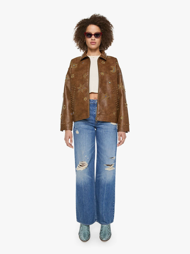 Full body view of a woman in a brown faux leather with celestial rhinestone details boxy jacket with drop shoulders, a zip closure and an oversized fit.