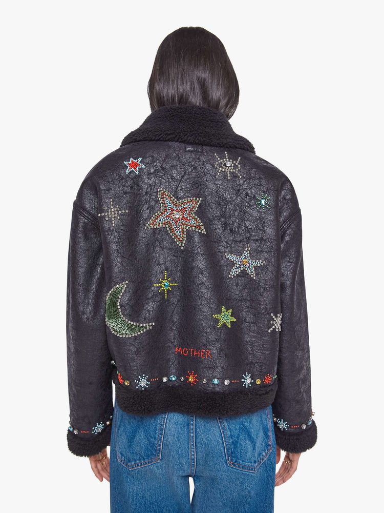 Back view of a woman in metallic black collared zip-up jacket with drop shoulders and a slightly cropped, boxy fit.