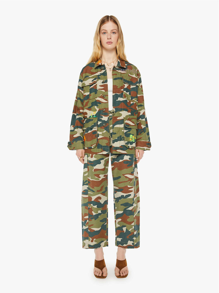 Full body view of a woman in an army jacket with  oversized patch pockets, slightly dropped shoulders, buttons down the front and an oversized fit. 