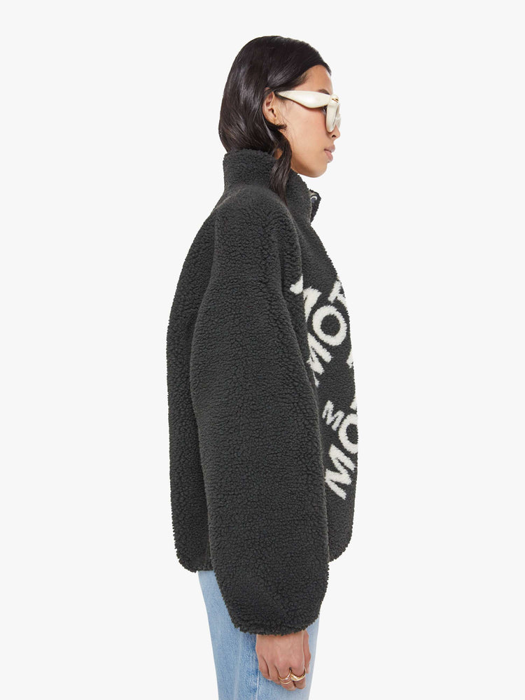 Side view of a woman in a reversible fleece jacket with a stacked collar, zip closure, patch pocket at the chest, slightly dropped shoulders and a loose fit.